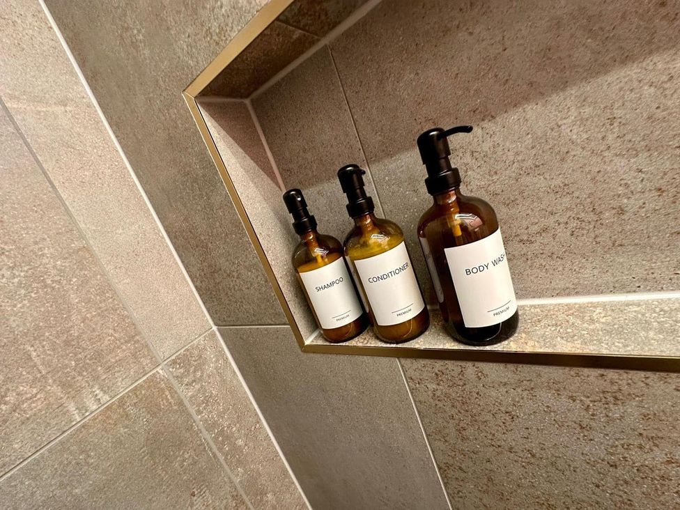Bathroom shelf with shampoo, conditioner, and body wash bottles at Luxurious guest house in Yorkshire with parking, Hemingbrough, Yorkshire