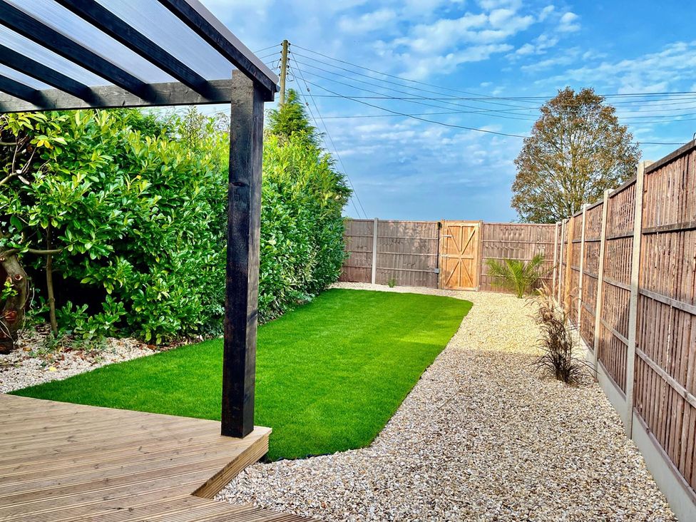 A garden with grass, fence, and a wooden deck at Luxurious guest house in Yorkshire with parking, Hemingbrough, Yorkshire