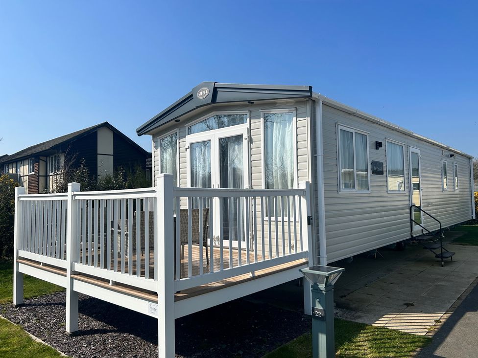 A mobile home with a deck and steps at a property in an outdoor setting
