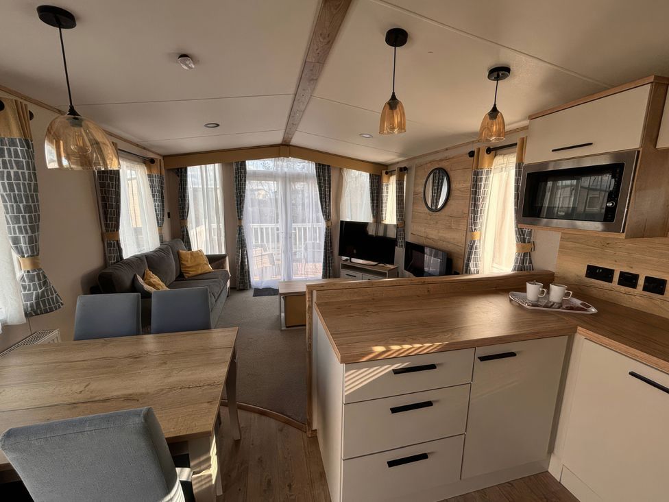 A living room with a sofa and dining area at a holiday home
