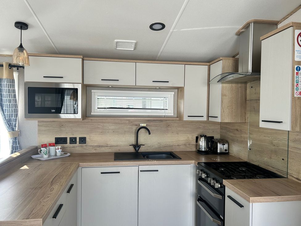 A kitchen with cabinets, sink, stove, and microwave at the property in 