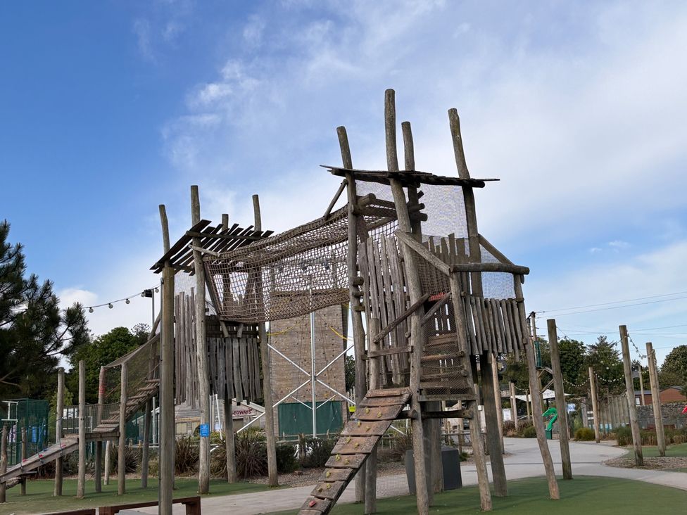 A climbing structure with a slide and netting in an outdoor play area at the park