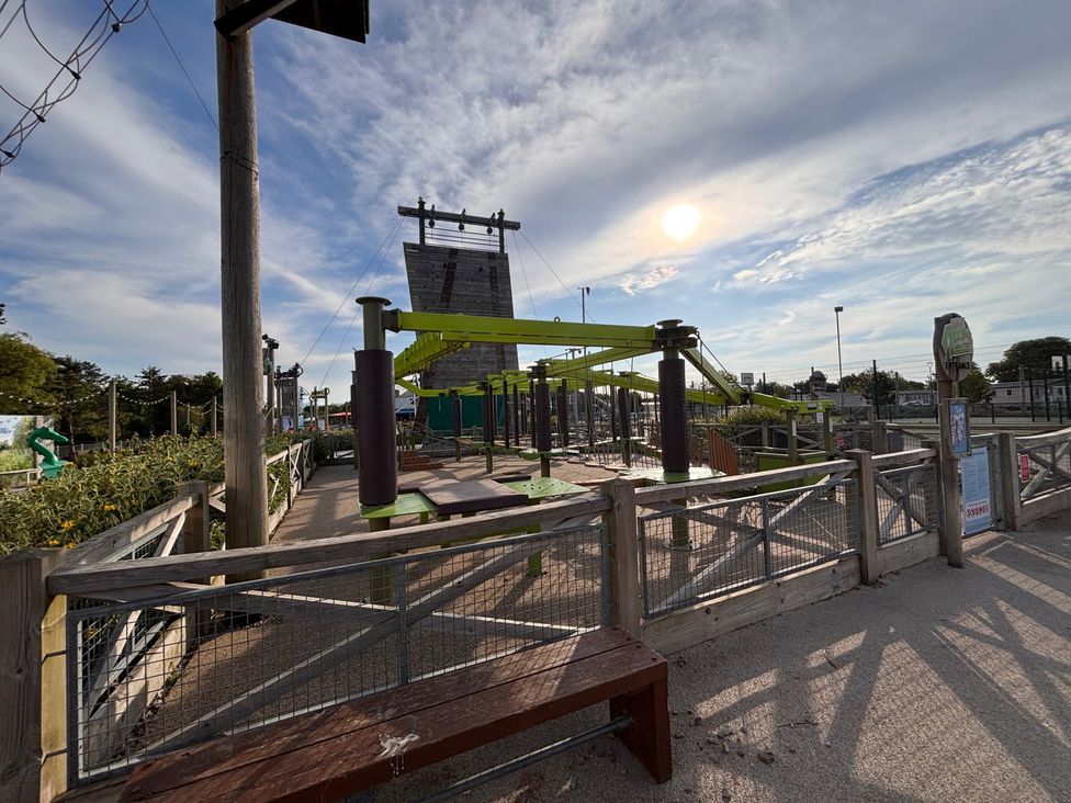 An outdoor obstacle course with climbing wall and benches at a recreational park