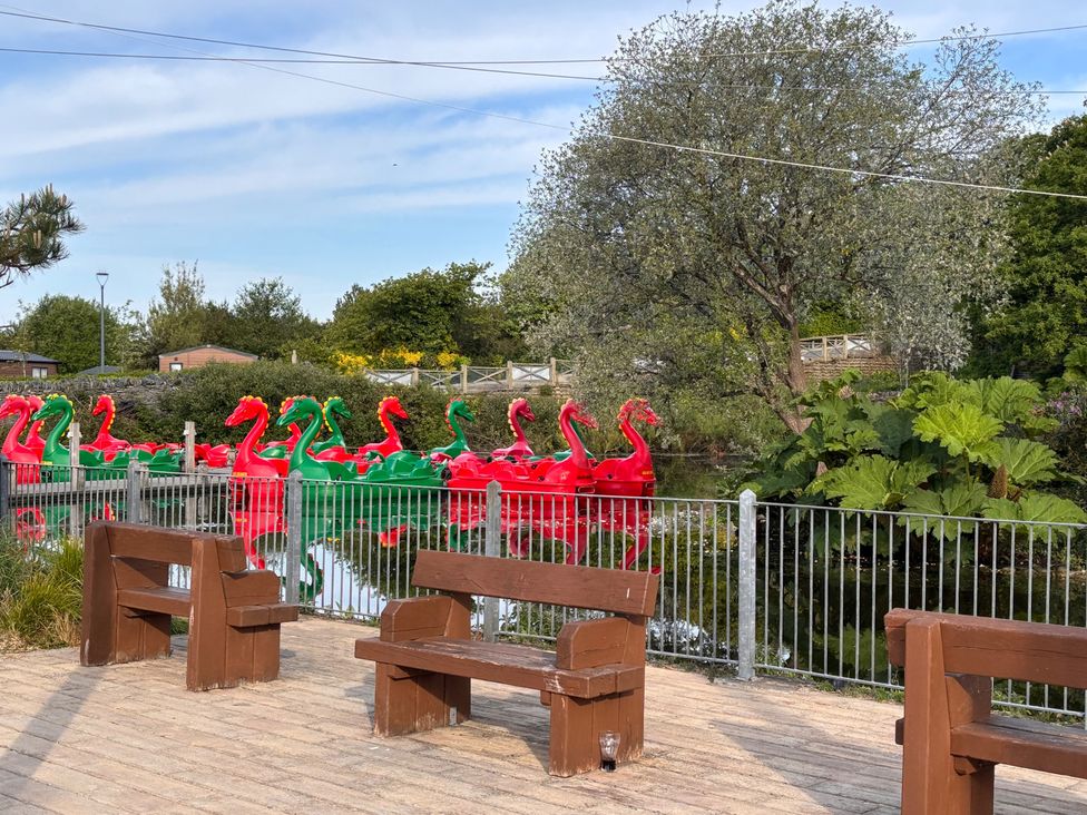 A pond with red and green swan boats and benches at a park
