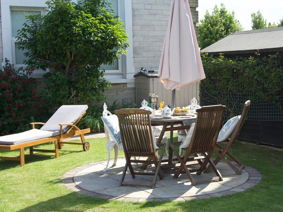 A garden with a table and chairs under an umbrella at Lovely, spacious apartment - sleeps 5 Ryde