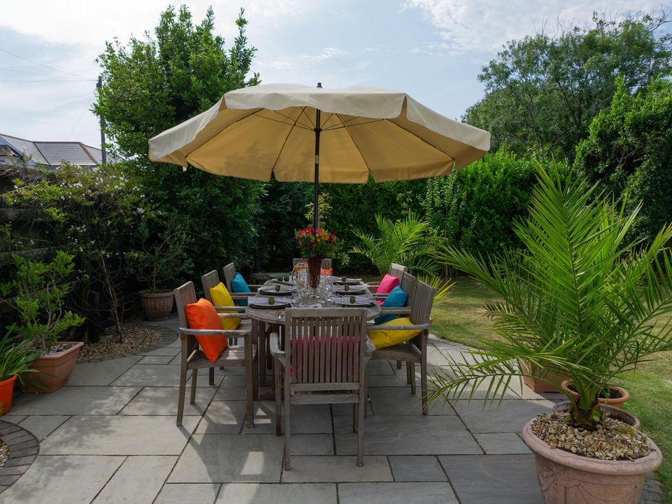 A garden with a dining table and chairs under an umbrella at Lovely, spacious apartment - sleeps 5 Ryde