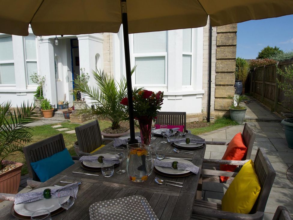 A dining table set with chairs and an umbrella at Lovely, spacious apartment - sleeps 5 in Ryde