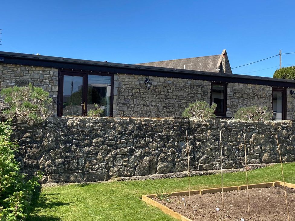 A stone wall with a garden bed in front at Vale of Glamorgan - Cottage - Sleeps 4 - Parking Llancarfan near St Athan