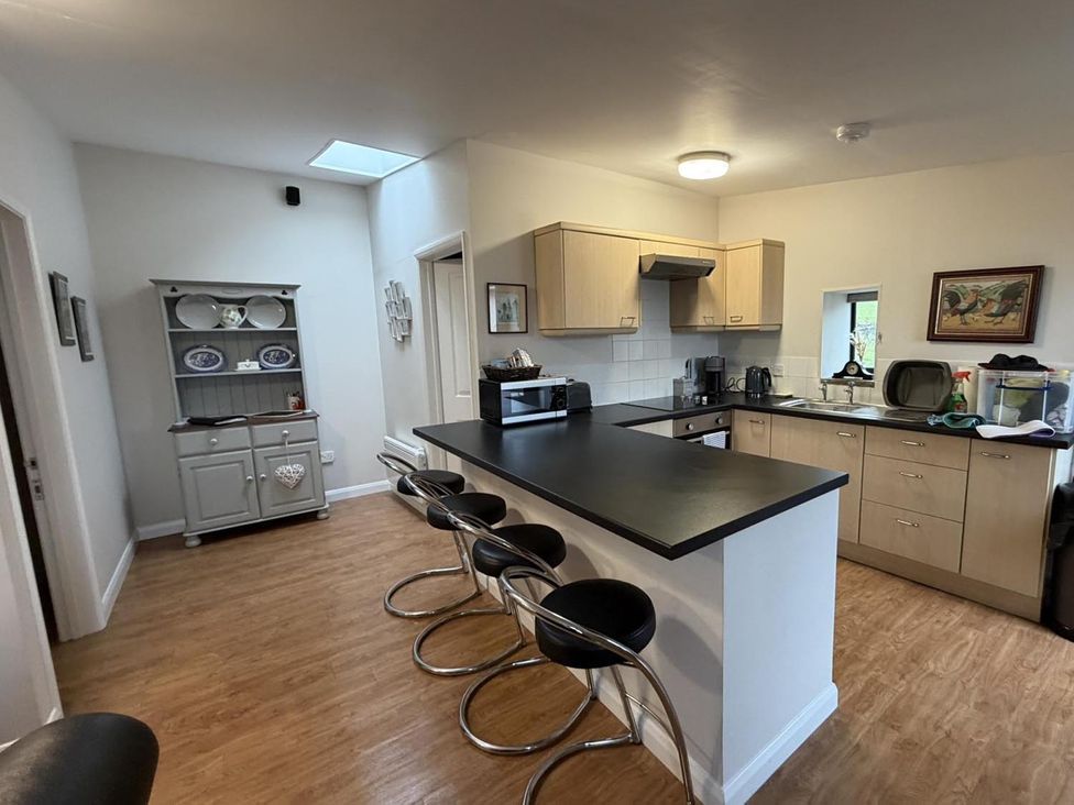 A kitchen with bar stools and various appliances at Vale of Glamorgan - Cottage - Sleeps 4 - Parking Llancarfan near St Athan