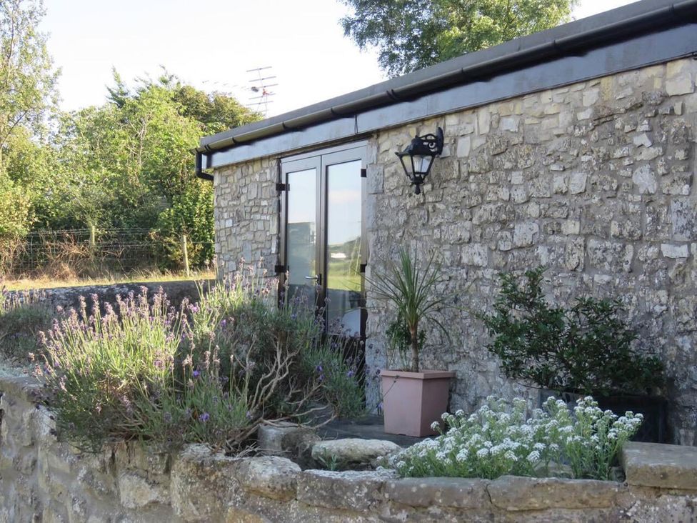 An outdoor area with a stone wall, plants and a wooden door at Vale of Glamorgan - Cottage - Sleeps 4 - Parking near Llancarfan