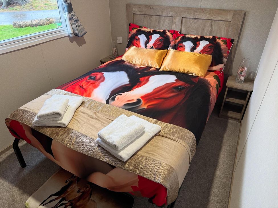 A bedroom with a double bed and horse-themed bedding at West Lawn 47 Haggerston Castle Paddock Views Haggerston