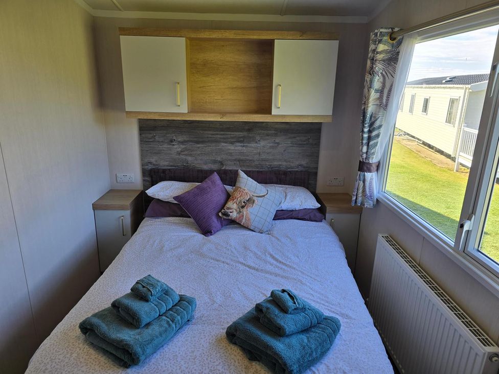 A bedroom with a bed and towels at 3 Bed-Sleeps 8-Free Parking-5 Min to Beach Embo near Dornoch