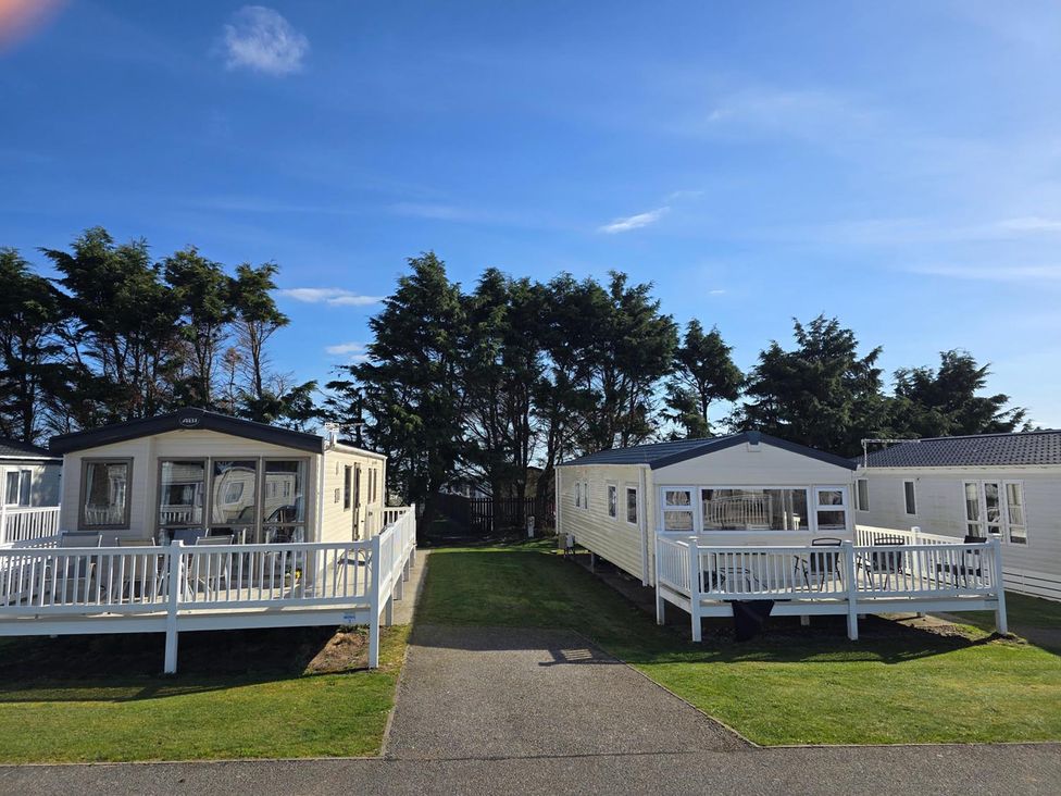 Two mobile homes with decks in a grassy area at 3 Bed-Sleeps 8-Free Parking-5 Min to Beach Embo near Dornoch