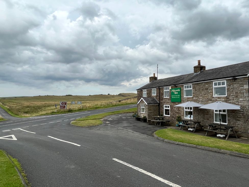 The exterior of Milecastle Inn on Hadrian's Wall near Haltwhistle with a road and signs