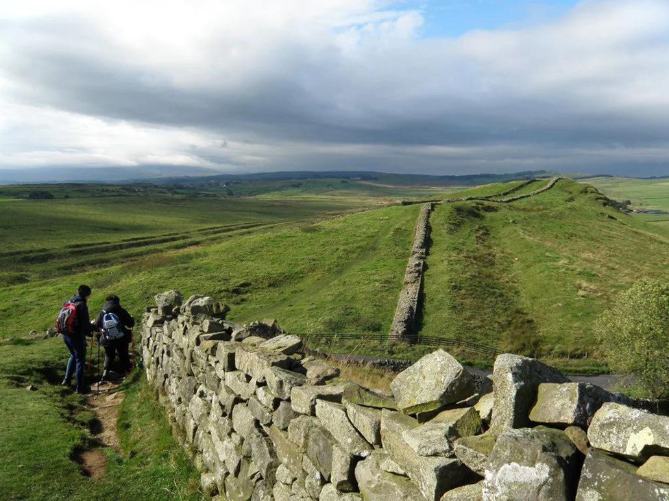 Hikers on a path by a stone wall along Hadrian's Wall near Haltwhistle