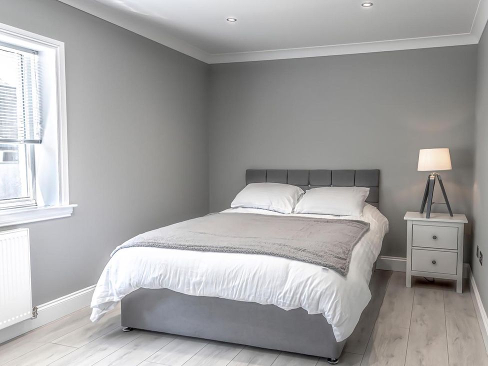 A bedroom with a bed, nightstand, lamp, and window at 1 Bed Cottage-Sleeps 2-Parking-Pets-Hot Tub in Kelty