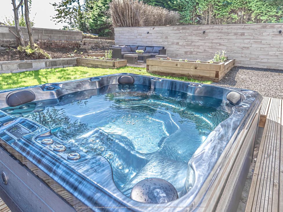 A hot tub with outdoor seating and planters in the garden at 1 Bed Cottage-Sleeps 2-Parking-Pets-Hot Tub in Kelty