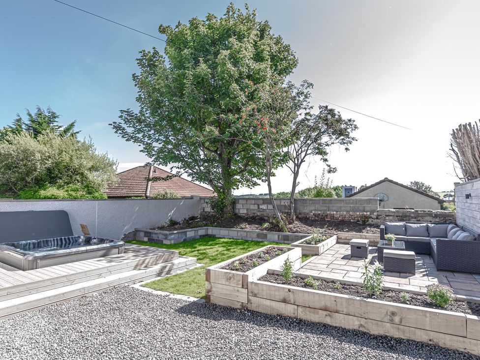 A garden featuring a hot tub, seating area, and planters at 1 Bed Cottage-Sleeps 2-Parking-Pets-Hot Tub in Kelty