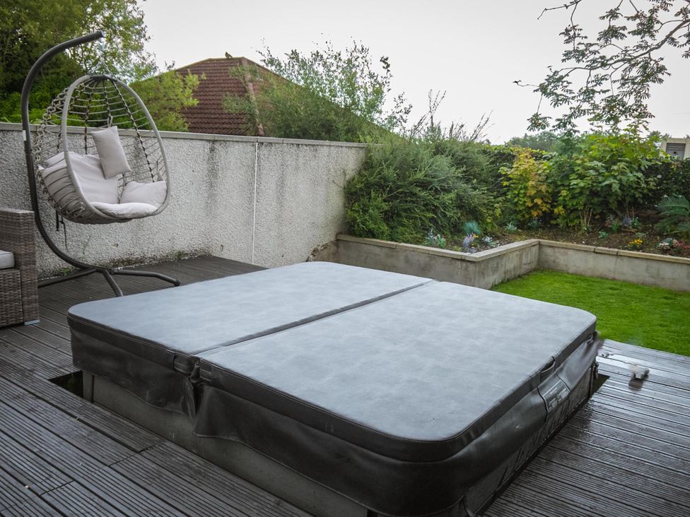 A garden with a hot tub and a hanging chair at 1 Bed Cottage-Sleeps 2-Parking-Pets-Hot Tub in Kelty