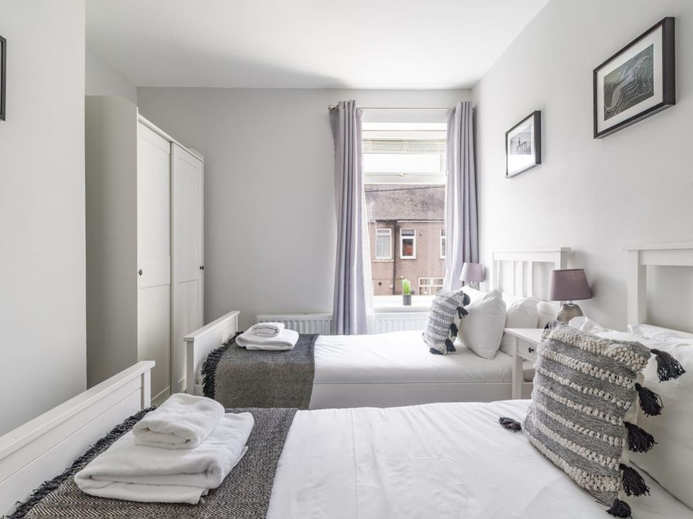 A bedroom with two beds and a wardrobe at East House-Sleeps 5-Pet friendly-Garden-Parking in Stakeford