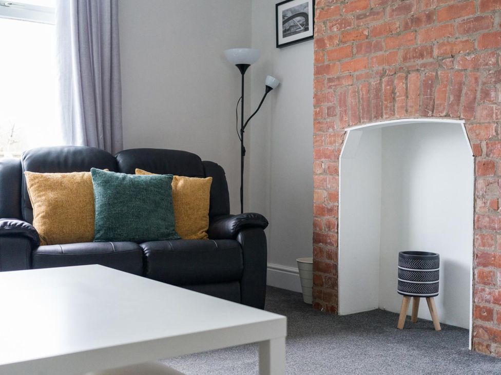 A living room with a sofa and cushions at East House-Sleeps 5-Pet friendly-Garden-Parking in Stakeford