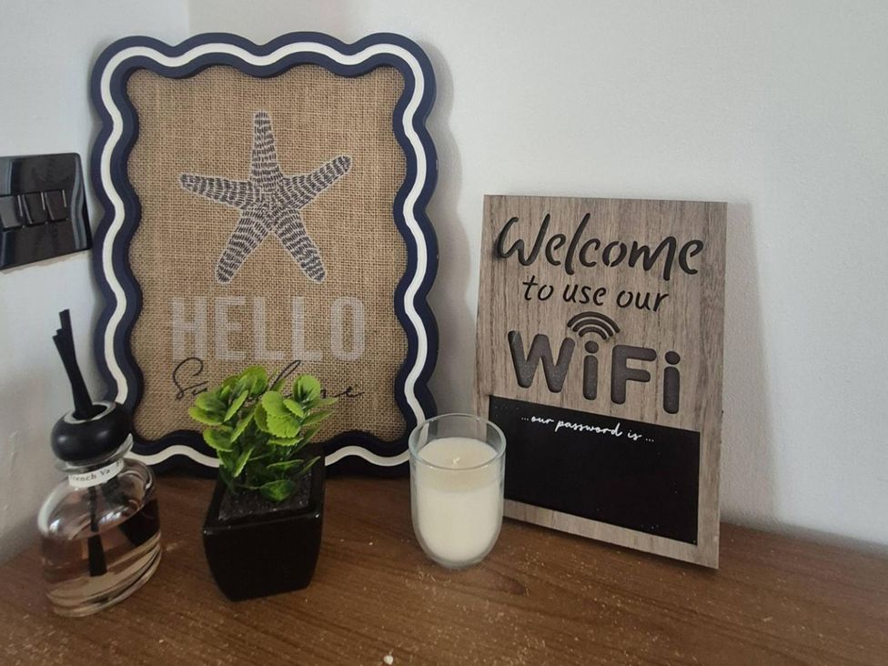 A welcome sign and decor items on a wooden table at Stylish Cornish Retreat, Sleeps 4 Near Hayle Beach