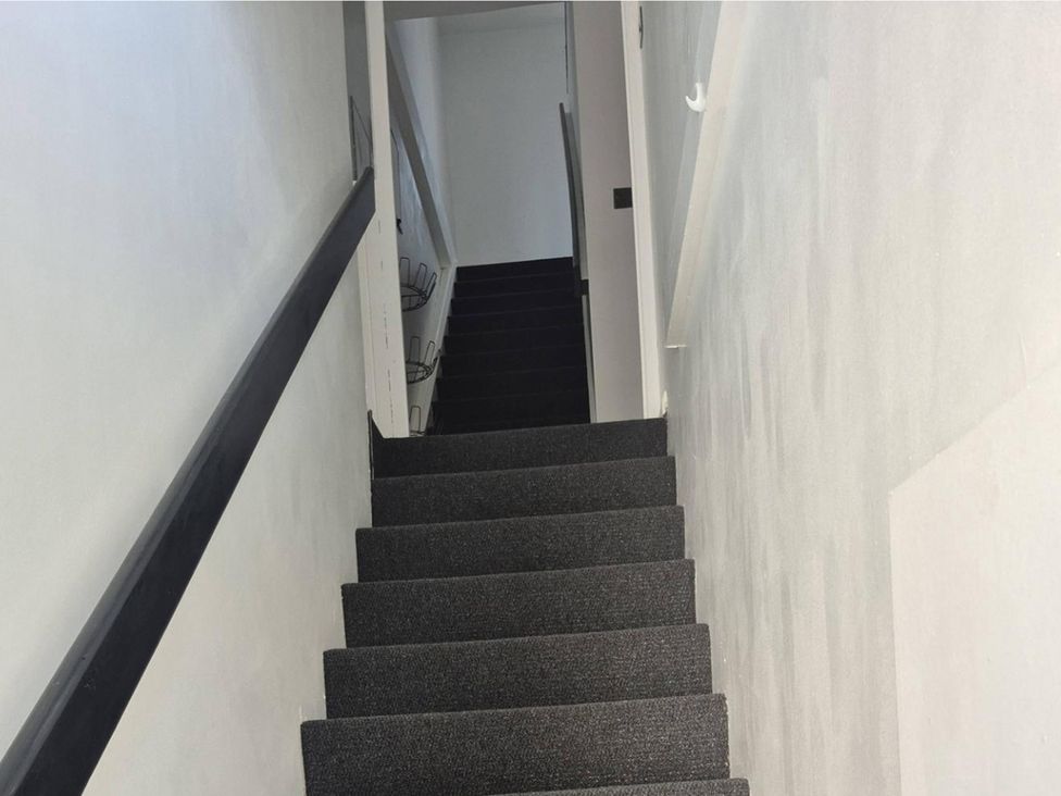 A staircase with black carpet and a handrail at Stylish Cornish Retreat, Sleeps 4 Near Hayle Beach, Hayle