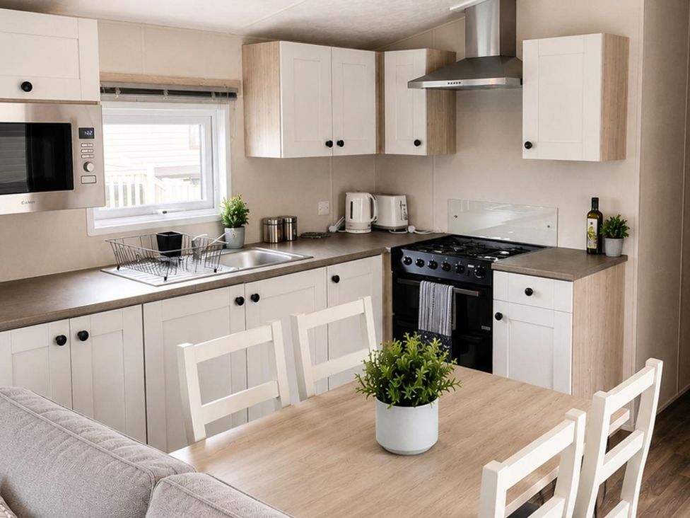 A kitchen with modern appliances and a dining table at 3 Bedroom Cabin Sleeps 6 - Shared Pool & Shared Hot Tub, Flamingo Land Resort near Malton