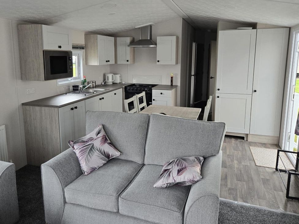 A kitchen with a couch, table, and appliances at 3 Bedroom Cabin Sleeps 6 - Shared Pool & Shared Hot Tub, Flamingo Land Resort near Malton