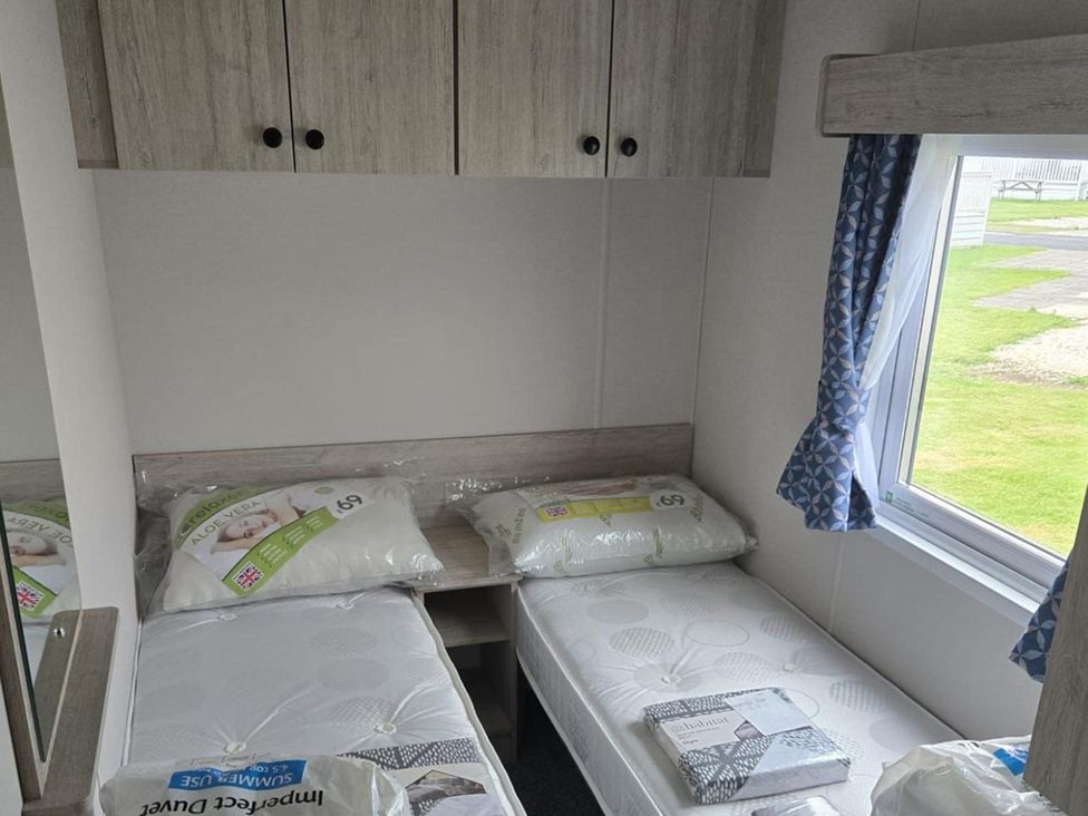 A bedroom with two single beds and a wardrobe at 3 Bedroom Cabin Sleeps 6 - Shared Pool & Shared Hot Tub near Flamingo Land Resort near Malton