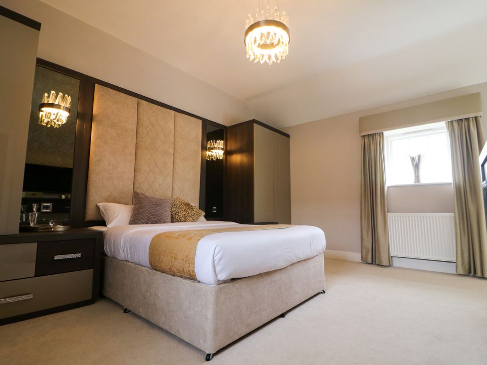 A bedroom with a bed and chandelier at Northumberland Luxury Stays - The Chivits West Chevington near Amble