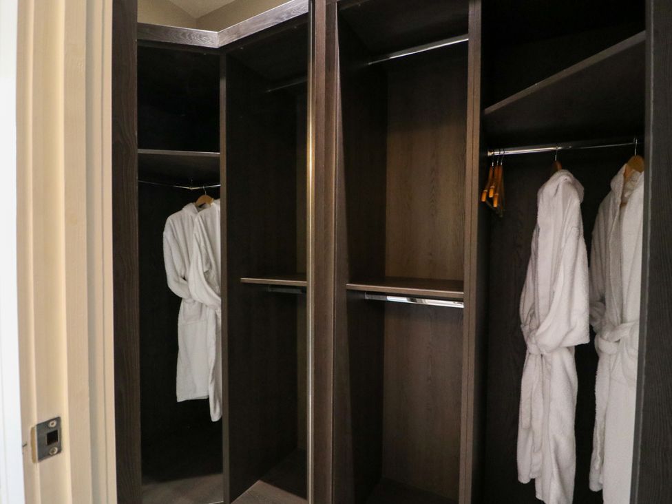 A closet with hanging robes and empty shelves at Northumberland Luxury Stays - The Chivits in West Chevington near Amble