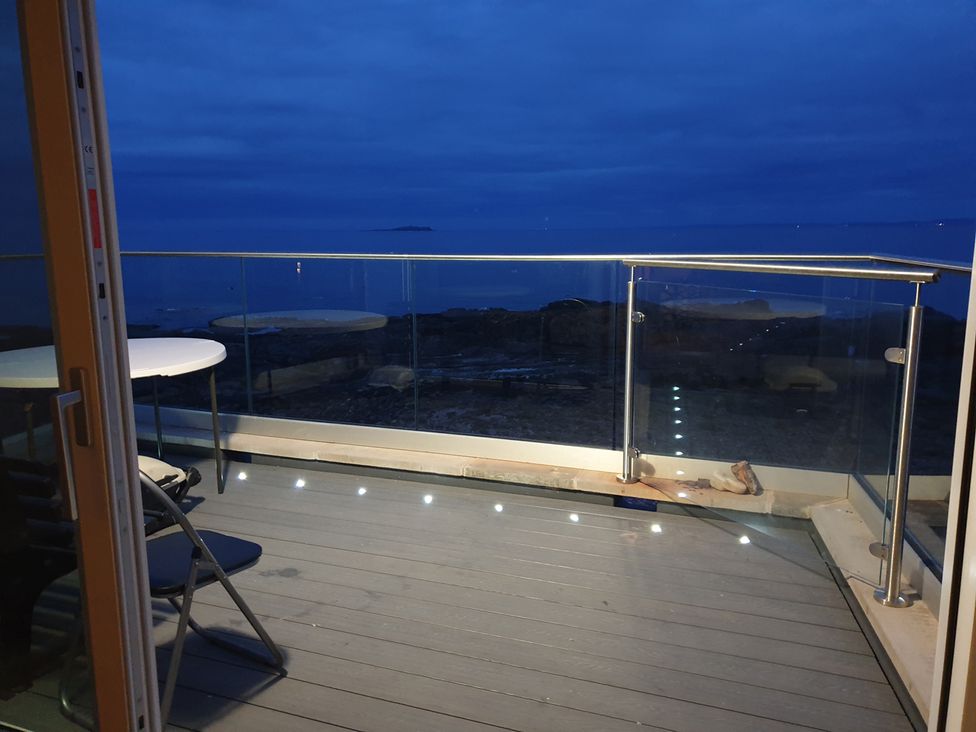 A balcony with a table and chair overlooking the sea at Cellardyke 3-Bed House, Sleeps 6 with Sea Terrace in Cellardyke