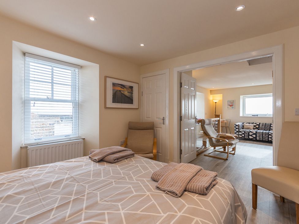 A bedroom with a bed and an armchair at Cellardyke 3-Bed House, Sleeps 6 with Sea Terrace in Cellardyke