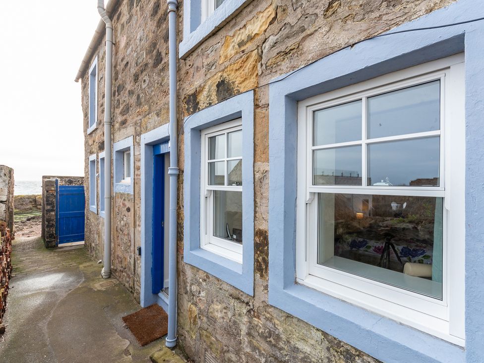 A blue door and windows on a stone wall at Cellardyke 3-Bed House, Sleeps 6 with Sea Terrace, Cellardyke