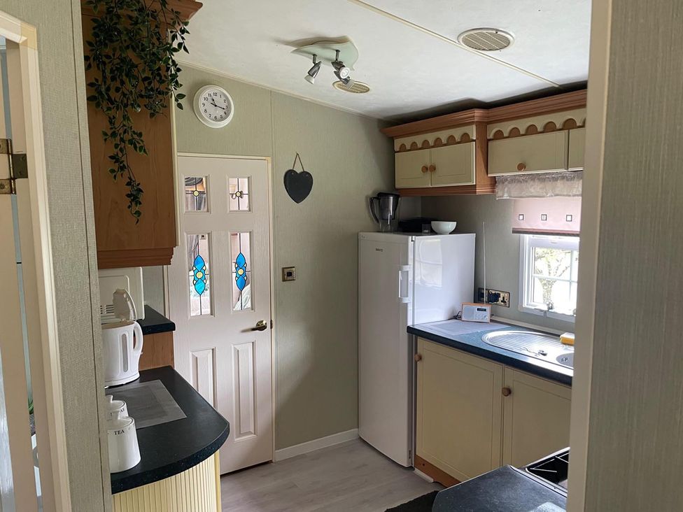 A kitchen with a fridge, sink, and cupboard at 2 Bed Lodge Sleeps 5 - Pet Friendly, WiFi, Parking, Skegness