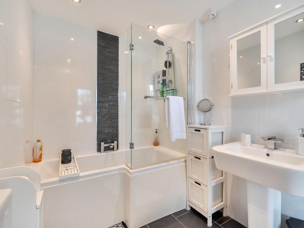 A bathroom featuring a bath, shower, sink, and cabinet at 1 Bed - Sleeps 4 - Parking - Pets - Town Centre Wadebridge