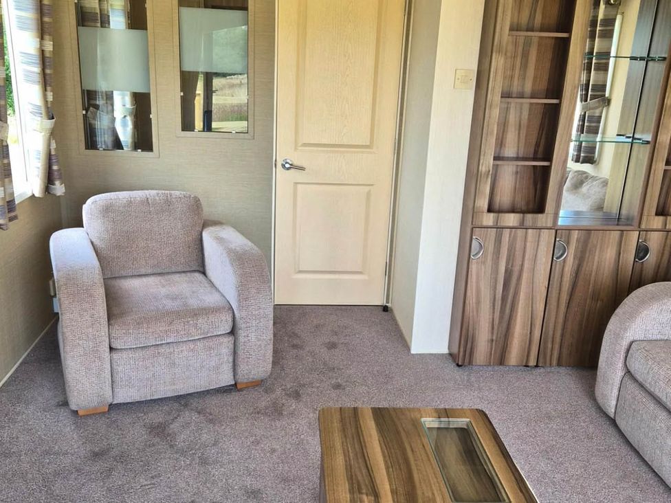 A living room with an armchair and a cabinet at Cabin - Sleeps 6 - Outdoor Pool and Parking, Cenarth