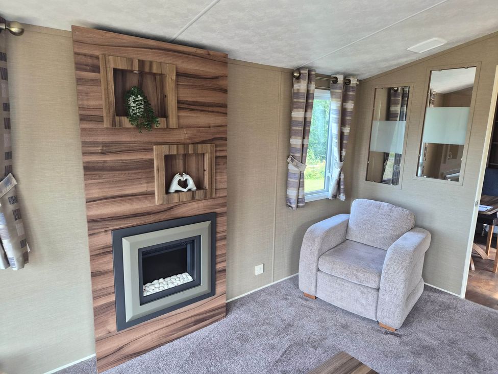 A living room with a fireplace and an armchair at Cabin - Sleeps 6 - Outdoor Pool and Parking, Cenarth