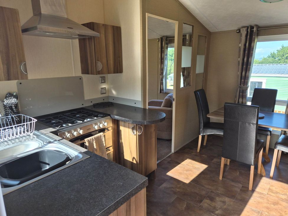 A kitchen with appliances and dining area at Cabin - Sleeps 6 - Outdoor Pool and Parking in Cenarth