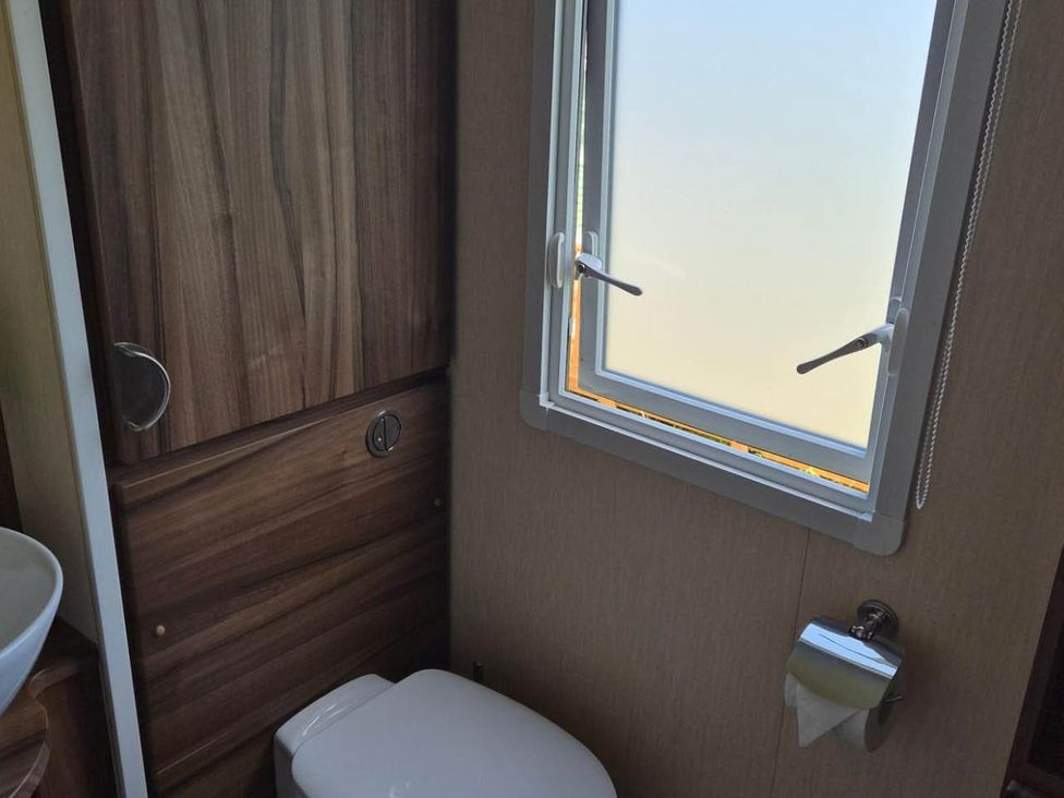 A bathroom with a toilet and window at Cabin - Sleeps 6 - Outdoor Pool and Parking Cenarth