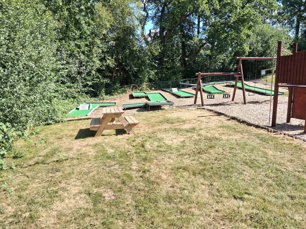 An outdoor area with a picnic table, swing set, and mini golf courses at Cabin - Sleeps 6 - Outdoor Pool and Parking in Cenarth