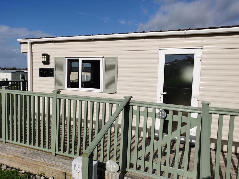 A mobile home with a deck and a sign outside at Snowdonia Sunbeach Holiday Sea and Mountain view, Llwyngwril