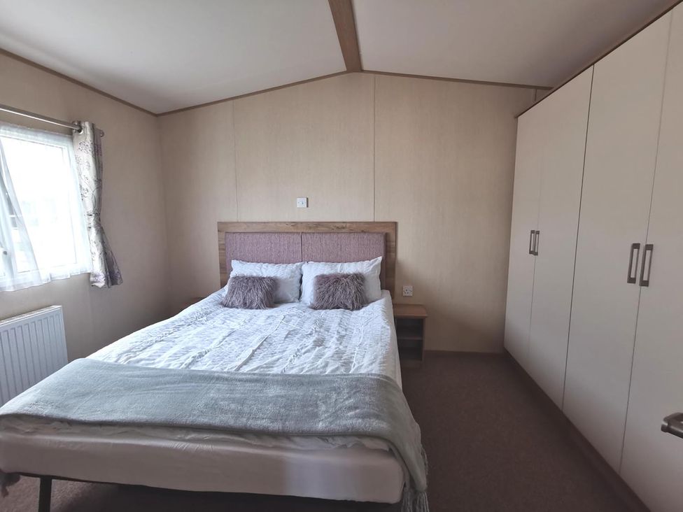 A bedroom with a bed and wardrobe at Snowdonia Sunbeach Holiday Sea and Mountain view in Llwyngwril