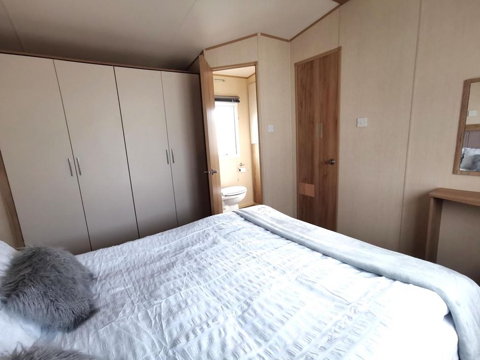 A bedroom with a bed and wardrobe at Snowdonia Sunbeach Holiday Sea and Mountain view, Llwyngwril