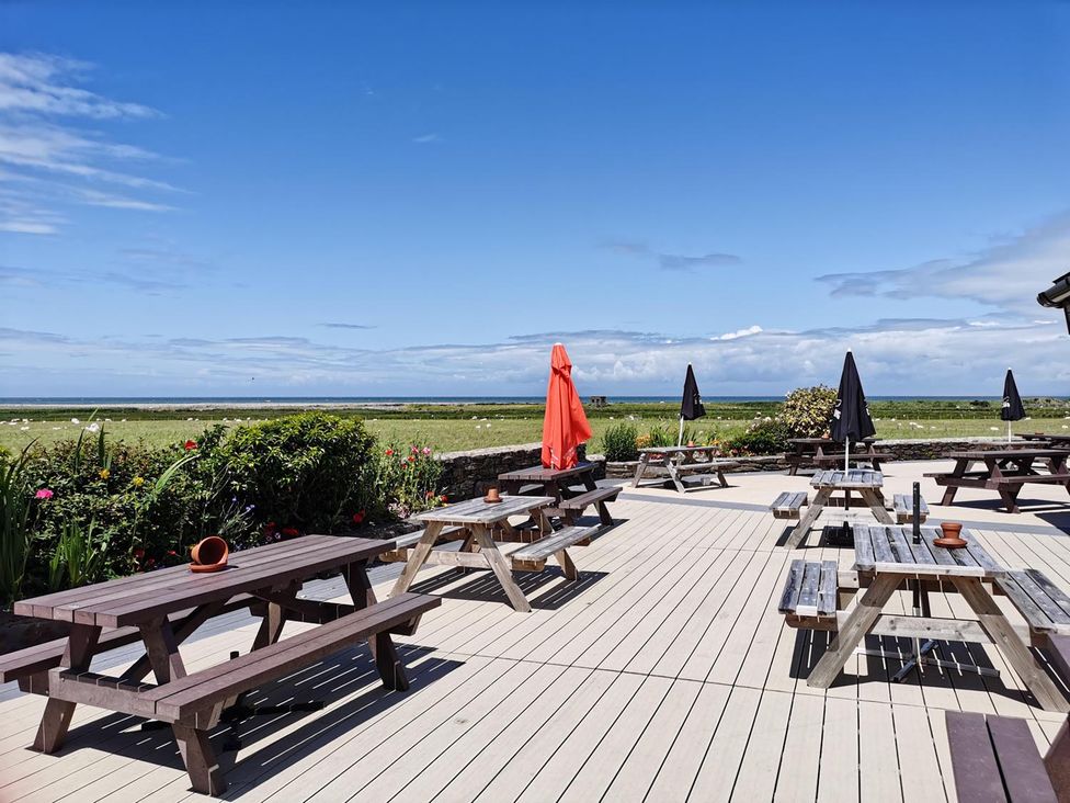 An outdoor seating area with tables and umbrellas at Snowdonia Sunbeach Holiday Sea and Mountain view, Llwyngwril