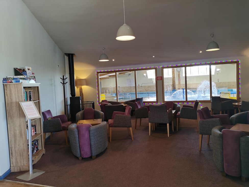A lounge area with armchairs and a bookshelf at Snowdonia Sunbeach Holiday Sea and Mountain view, Llwyngwril