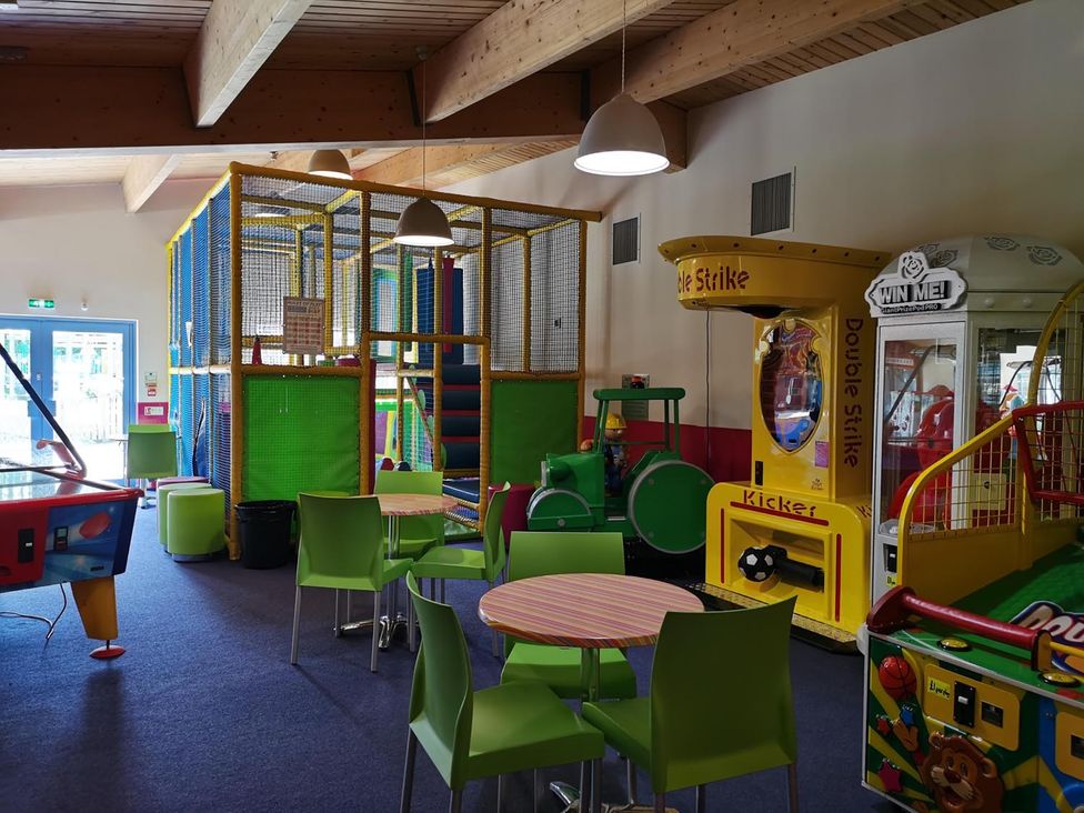 A play area with arcade machines and dining tables at Snowdonia Sunbeach Holiday Sea and Mountain view, Llwyngwril