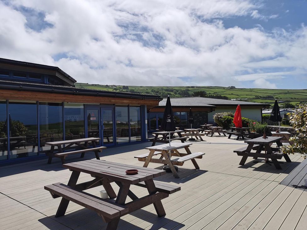 An outdoor seating area with tables and umbrellas at Snowdonia Sunbeach Holiday Sea and Mountain view in Llwyngwril