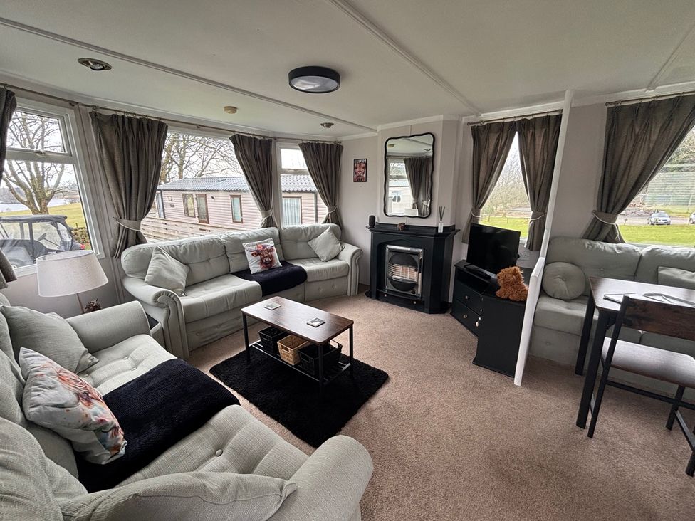A living room with a fireplace and television at No 38 Heilan Hoose at Three Lochs Newton Stewart